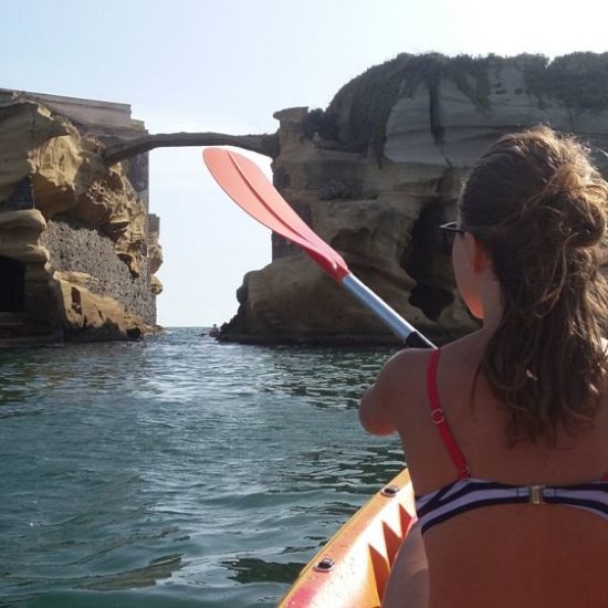 Ragazza in kayak rema nella zona della Gaiola, Posillipo.